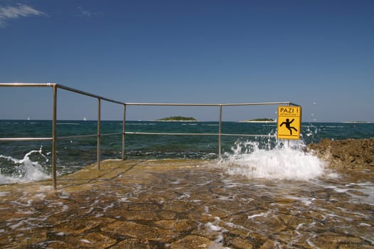 Wave crashing on the shore with attention sign