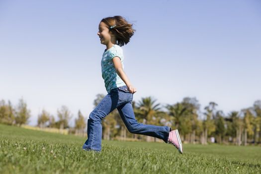 Smiling Young Girl Running on Grass in Park