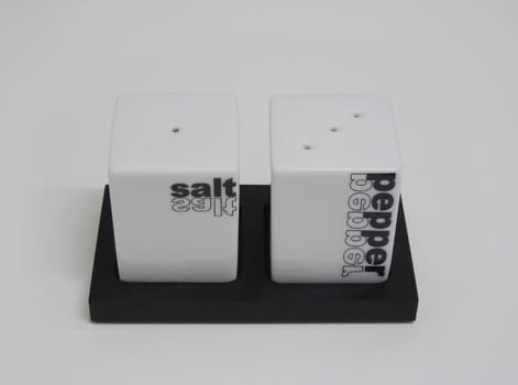        Frontal view of a black and white saltcellar and peppershaker .