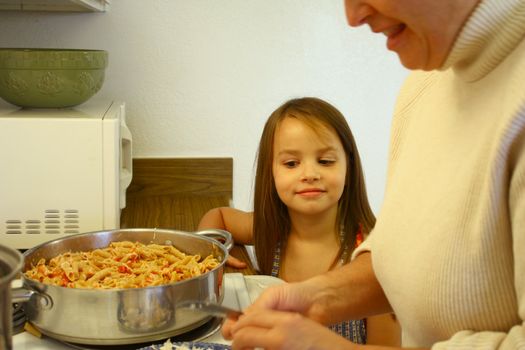 Little girl helping Mom cook at the stove in the kitchen.