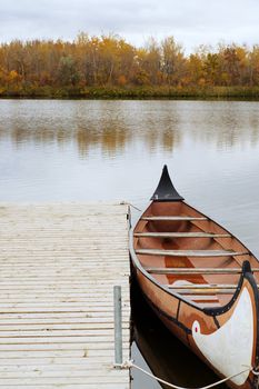 A canoe docked and floating on the river, shot on a cloudy day