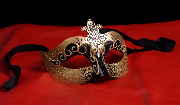 An intricate venetian mask shot on red leather