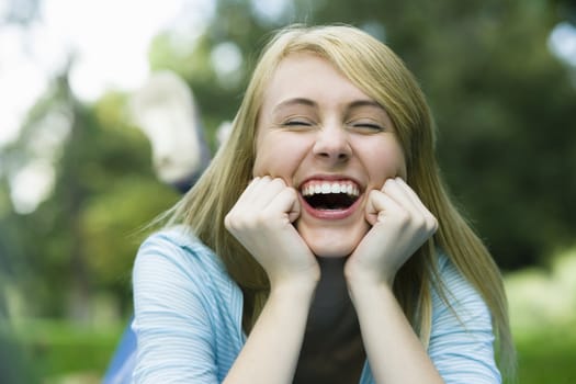 Laughing Teen Girl Lying in a Park with Head Resting on Her Hands