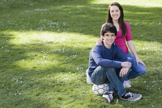 Two Smiling Teenagers on Lawn with Soccer Ball