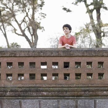 Smiling Teen Boy Outdoors Looking over Wall
