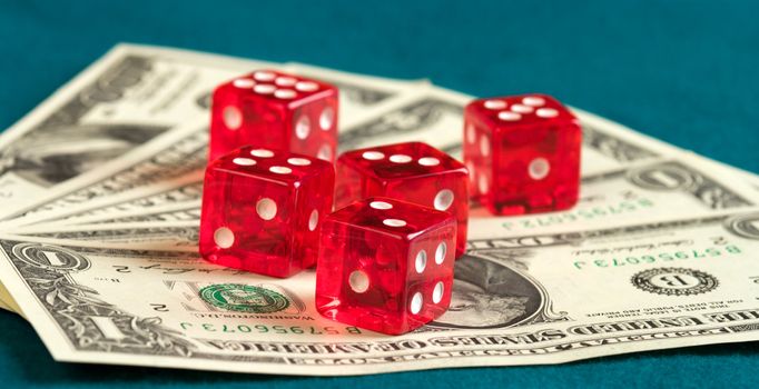 Five red dice  lie on dollar banknotes.