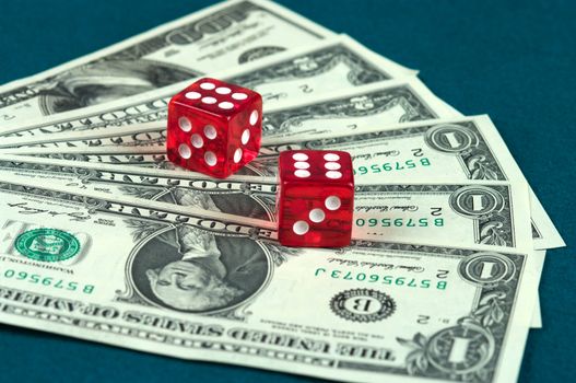 Red dice  lying on the dollar denominations spread out by a fan.