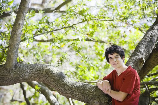 Smiling Teenage Boy in Red Shirt Standing in Woods