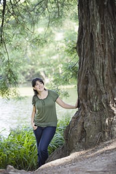 Woman looking up to Sky Standing Next to  Tree