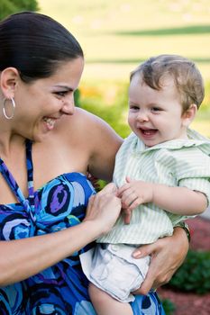 A young mother tickles her baby happily.