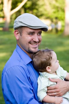 A proud young father holding his cute baby boy with a smile on his face.