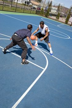 A young basketball player guarding his opponent during a one on one basketball game.