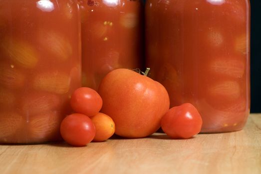 Mason jars full of canned tomatoes shot on a wooden cutting board