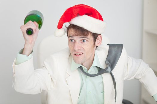 The young guy in a white jacket and a christmas hat brawls with a bottle in a hand