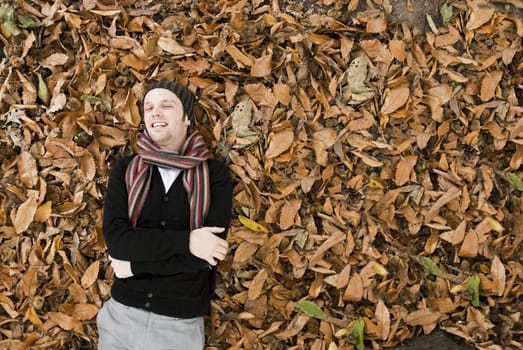 High angle portrait of young man laying on the yellow leaves covered ground.
