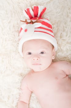 Newborn baby in chritstmas hat lies on fur