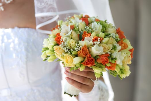Multi-coloured bouquet in the hands of bride.
