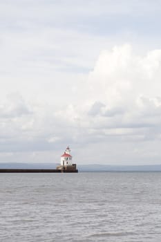 Lighthouse on end of rocky pier by lake