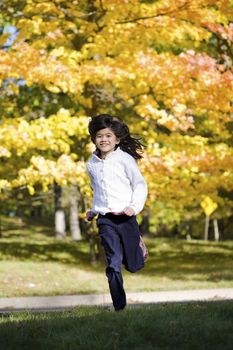 young girl running against background of colorful autumn leaves