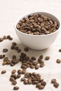 Roasted coffee beans in a white bowl on jute sacking