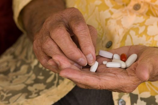 senior hand sorting through a handful of medications