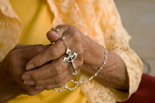 elderly caucasian hands holding a silver rosary