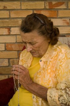 elderly caucasian woman with hands folded in prayer