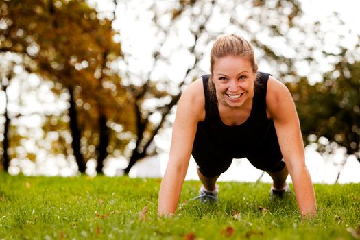 A woman doing push-ups in the park