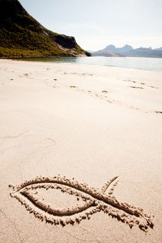 A fish symbol in drawn in the sand