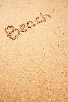 Beach written in the sand on the coast with mountains in the background