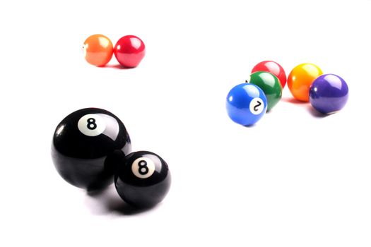 Spheres for game in billiards, in the foreground two black spheres with number eight, one big, other small.