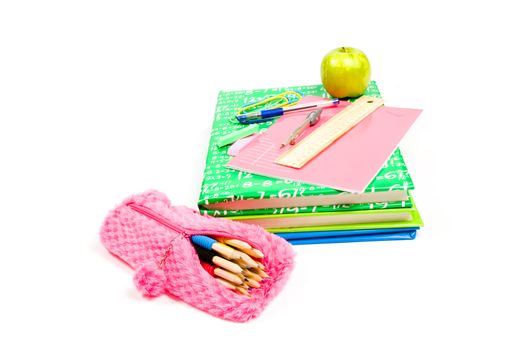 stack of books with school supply and green apple on white 

