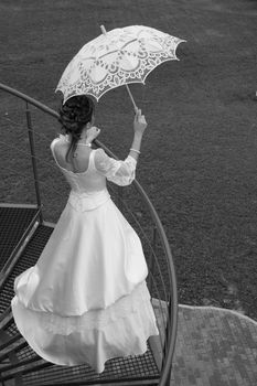 Black and white photo. Bride with umbrella waiting for her beloved.
