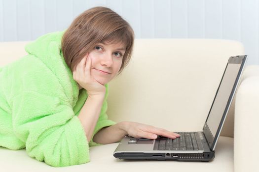 Portrait of the young woman in a dressing gown with the laptop
