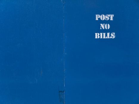 Blue wooden panel background with a white stenciled "post no bills" text.