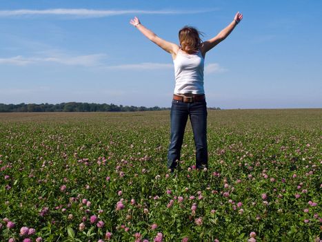 Beautiful attractive young happy woman girl jumping in a sunny flowers field