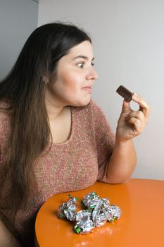Stout woman contemplating over wrappers of sweets