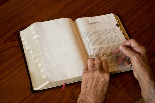 elderly caucasian hands over an open bible