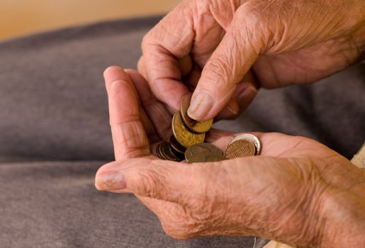 elderly caucasian woman counting coins in her hands