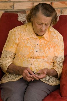 elderly caucasian woman counting coins in her hands