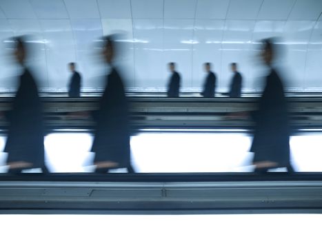 Very similar people walking on the same direction through a shiny tunnel. Blurred motion.