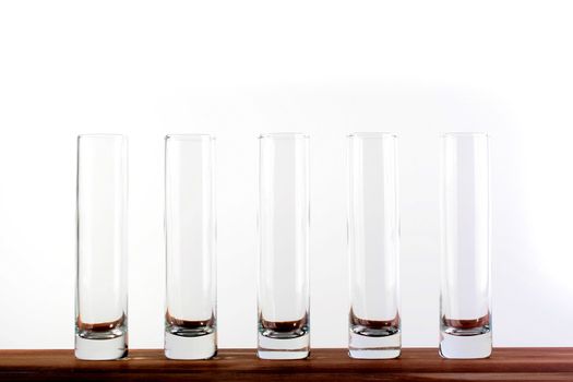 Five empty high narrow glasses on white background