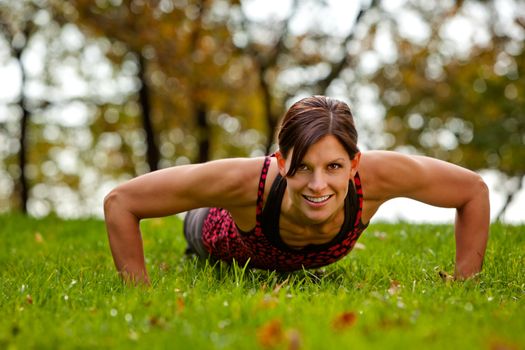 A caucasian female doing push ups in the park