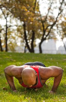 An african american male doing push ups in a park