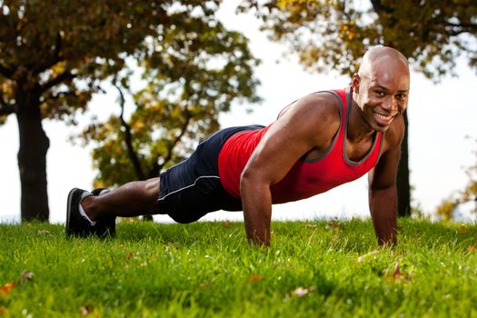 A man doing a push up in a park