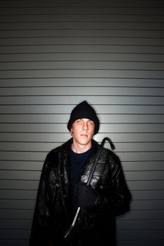 Young burglar in leather jacket with crowbar