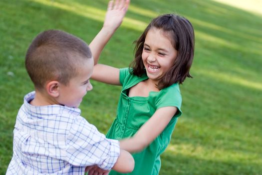 A little girl swings her arms at her brother as they rough house playfully.  Slight motion blur on the arms.