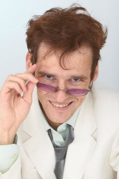 The cheerful tousled guy looks over eyeglasses