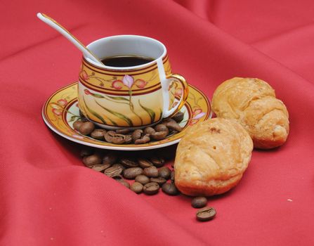 Heap of coffee bean and the cup on a red background