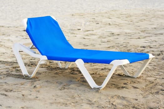 Blue plastic beach chair in a deserted beach